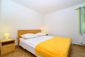 Una cama individual con cabecera de madera, dos lámparas de noche, una mesita de noche y una manta amarilla.