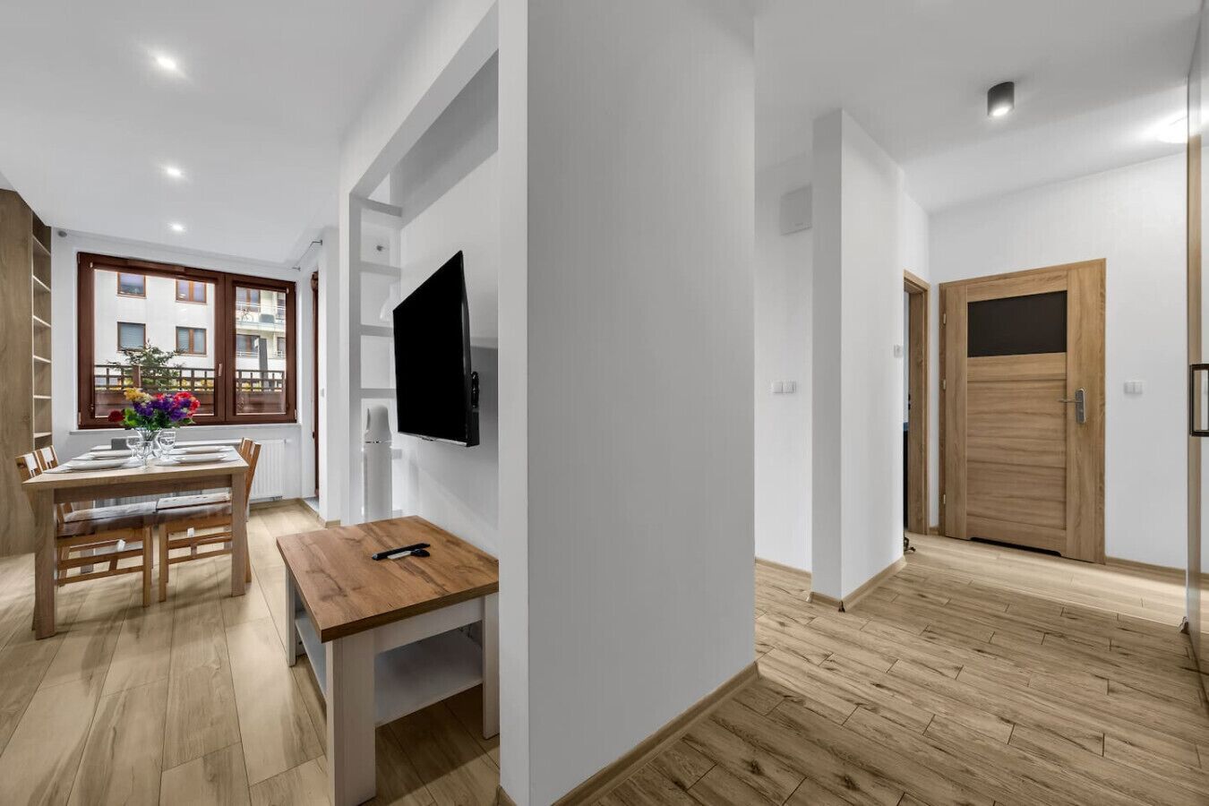 Ein modernes Apartment mit Essbereich, einem flachbildfernseher an der Wand und einer Holztür.
