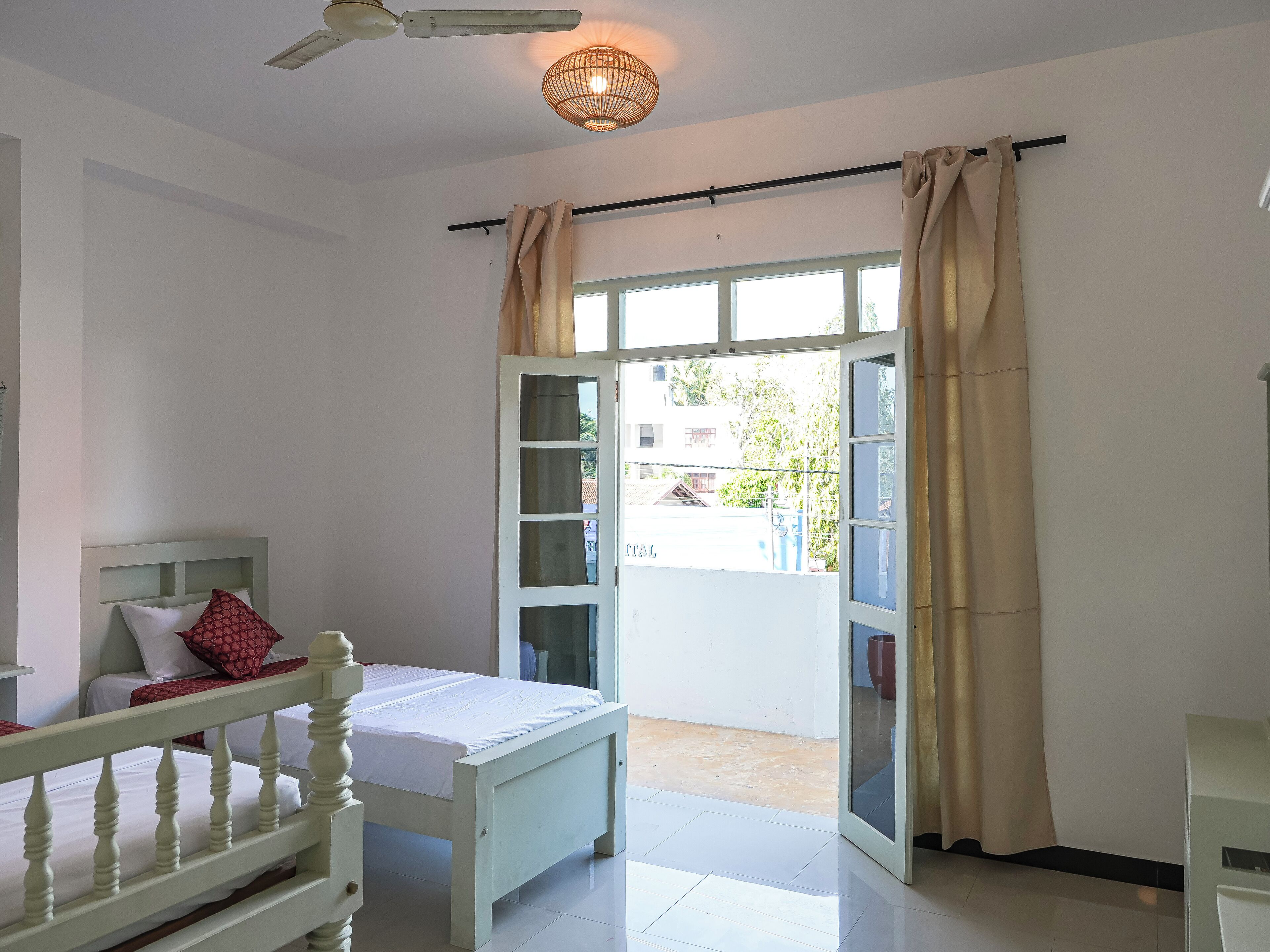 A bedroom with a bed, a ceiling fan, a window with curtains, and a view of the outside.