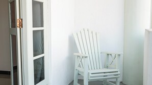 A white chair against a white wall, next to a white door with glass panels. - Mira Mirissa  (Mirissa)