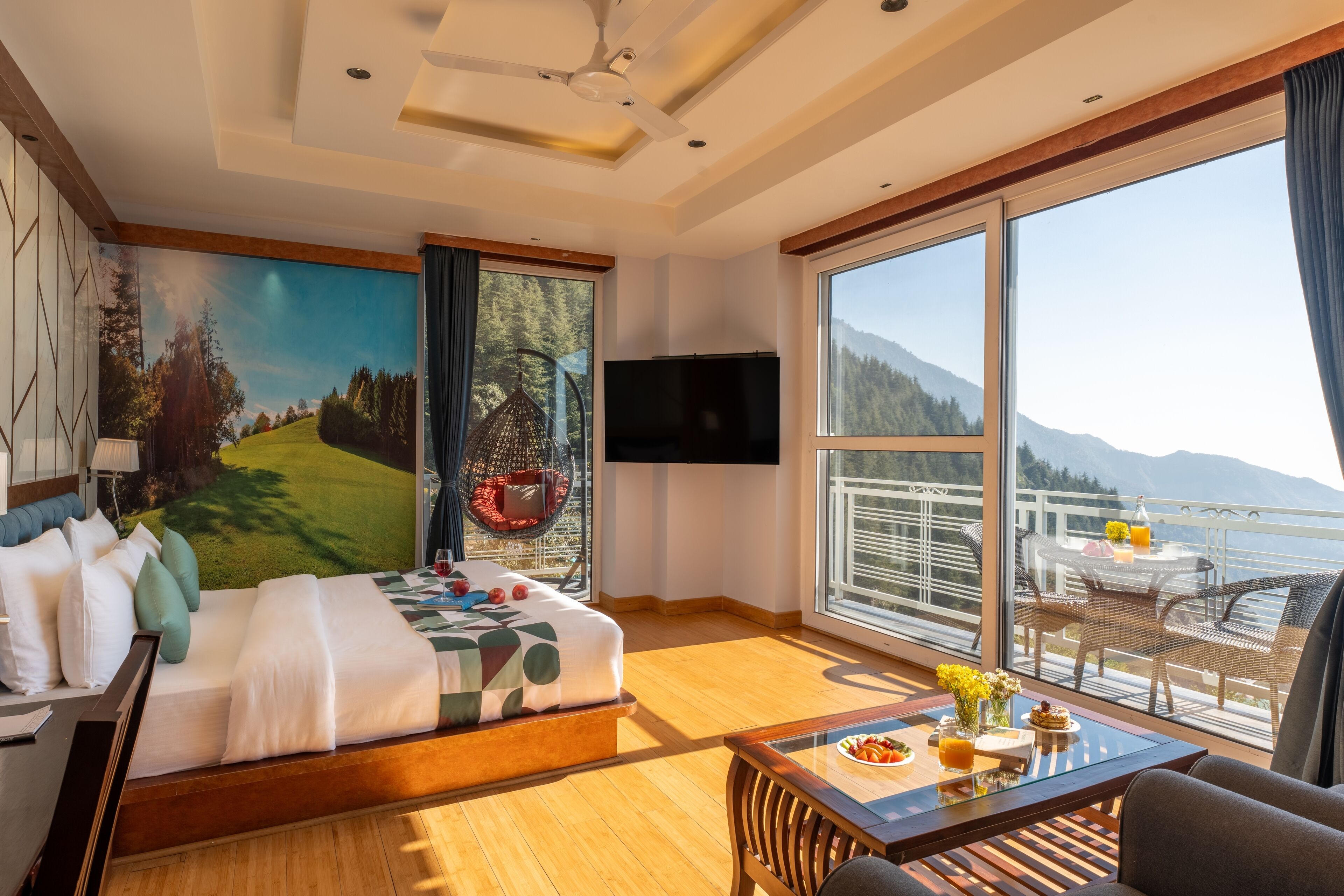 Une chambre d’hôtel moderne dotée d’un grand lit, d’une table à manger, d’une télévision et d’un balcon offrant une vue panoramique sur les montagnes.
