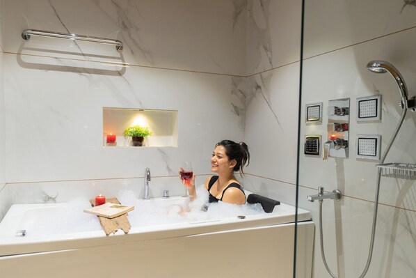 A modern bathroom with a bathtub, a glass-enclosed shower, and a vanity with a mirror. - Moustache Select Mcleodganj (Dharamshala)