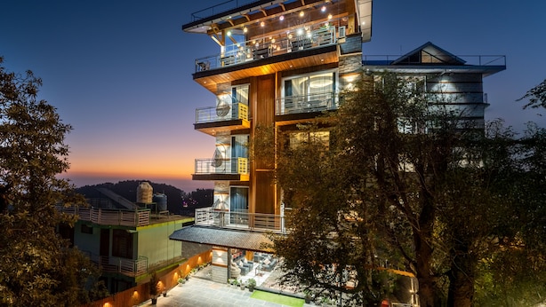 A multi-story building with balconies, outdoor seating, and a view of the surrounding landscape. - Moustache Select Mcleodganj (Dharamshala)