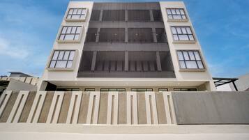A modern multi-story building with a flat roof, large windows, and a central atrium.