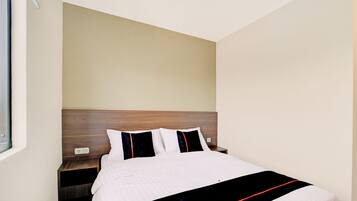 A hotel room with a bed, wooden headboard, and a nightstand.