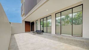 Een modern gebouw met een overdekt terras, voorzien van stenen vloeren en grote glazen deuren.