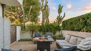 An outdoor patio with a fire pit table, wicker furniture, and cacti. - 2 Condos | Steps to the Beach + Hot Tub | Trestles Trailhead Duo by AvantStay (San Clemente)