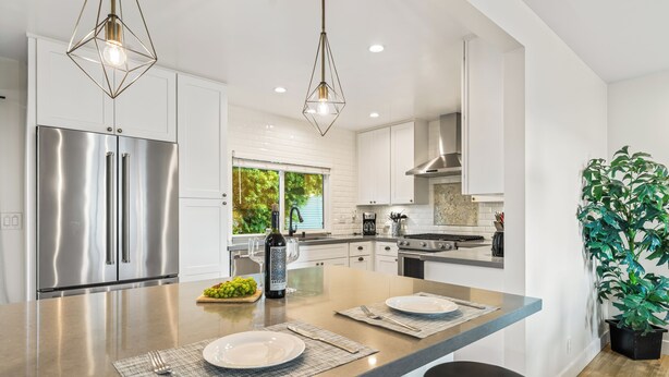 A modern kitchen with stainless steel appliances, a central island with seating, and pendant lighting. - 2 Condos | Steps to the Beach + Hot Tub | Trestles Trailhead Duo by AvantStay (San Clemente)