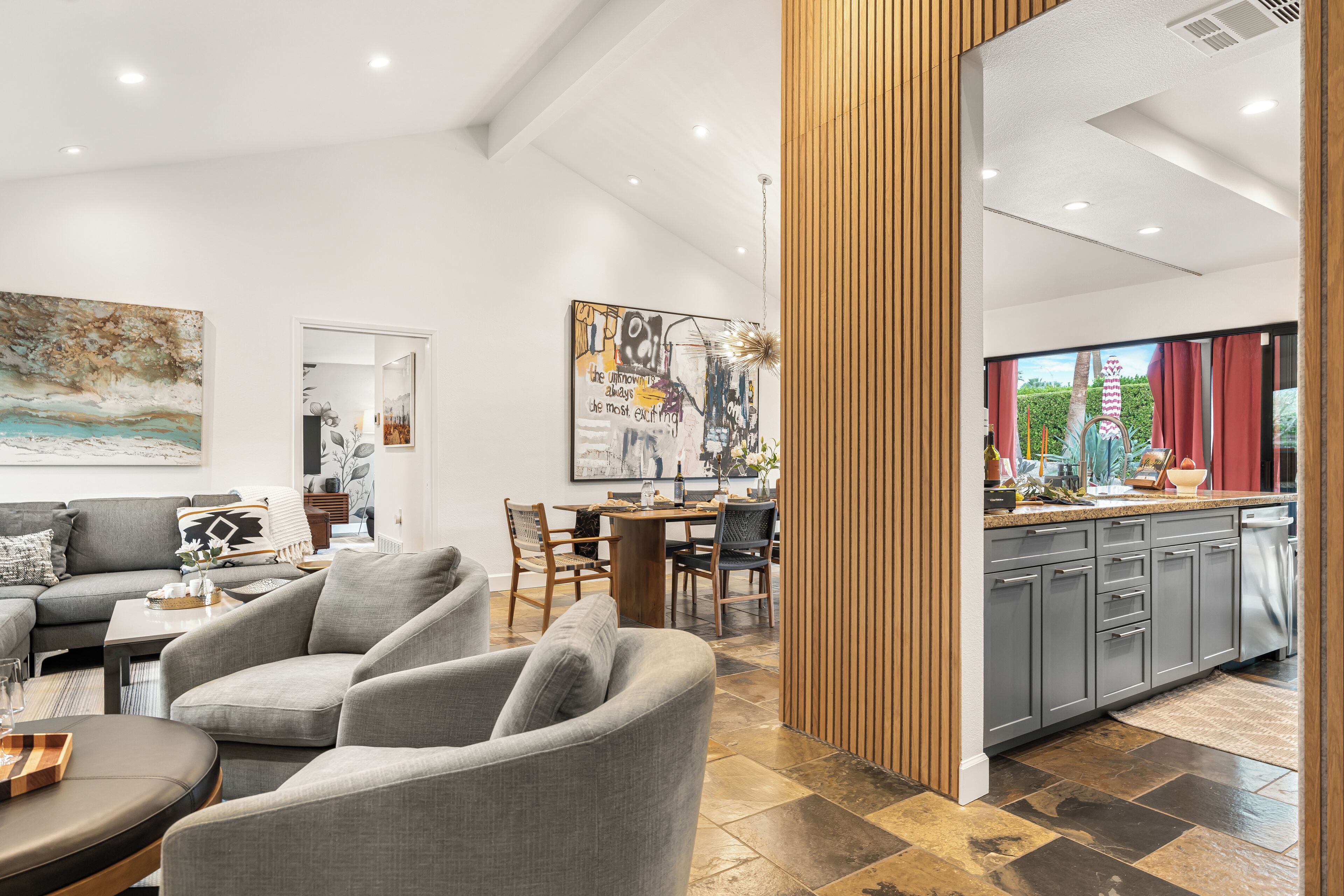 A modern living room with a sofa, chairs, a dining table, and artwork on the walls.