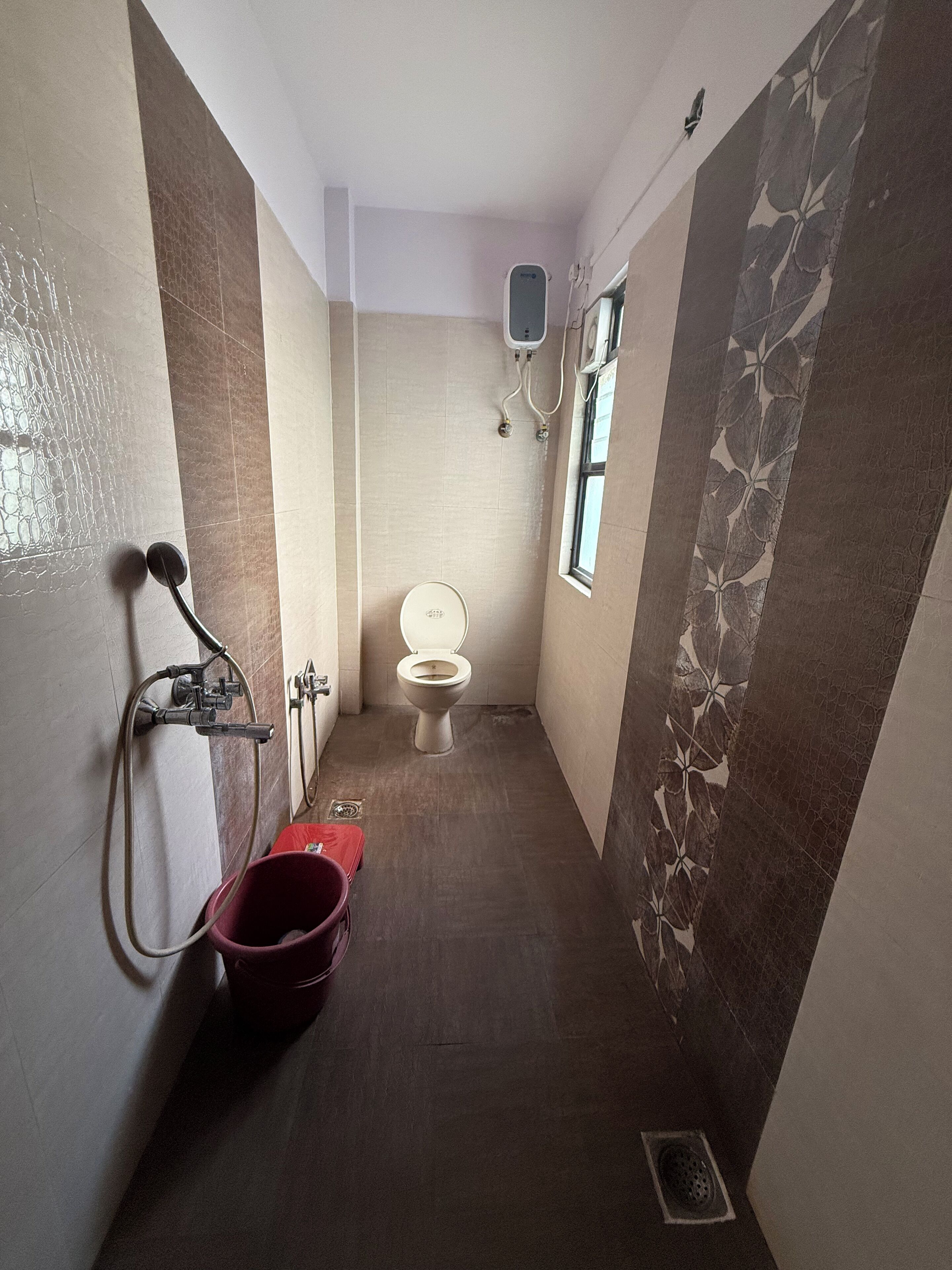 Un baño pequeño con inodoro, ducha y un cubo rojo.