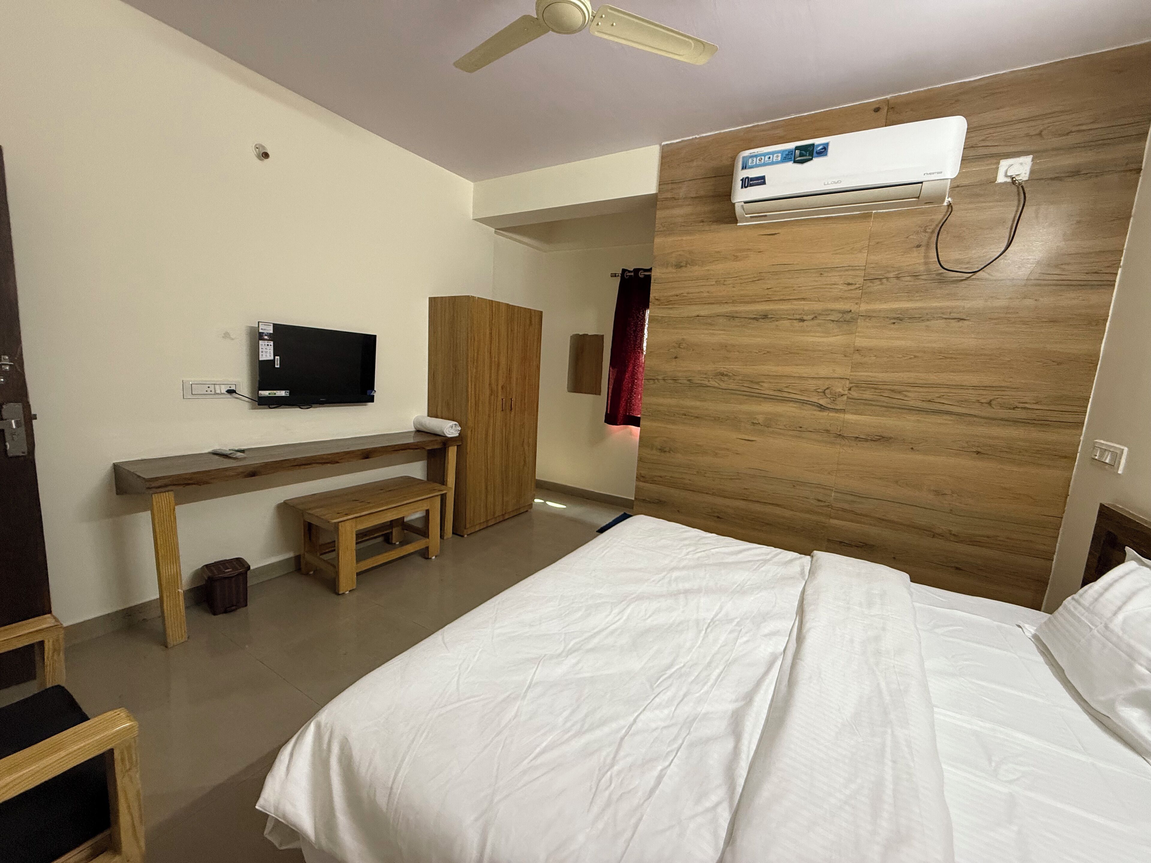 Una camera d'albergo con un letto, una scrivania, una televisione e un condizionatore d'aria.