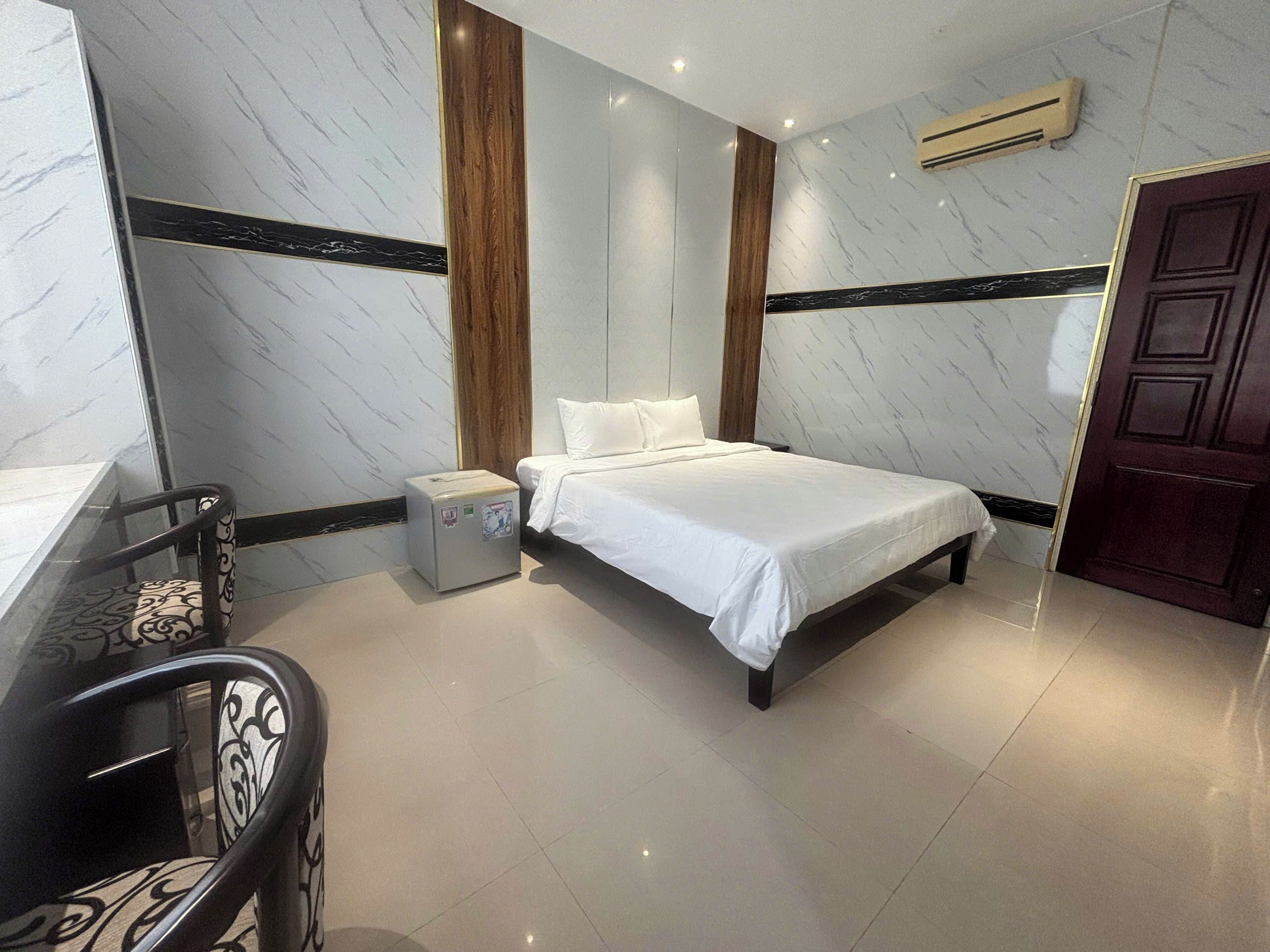 A hotel room with a bed, bedside table, and a small desk with a chair.