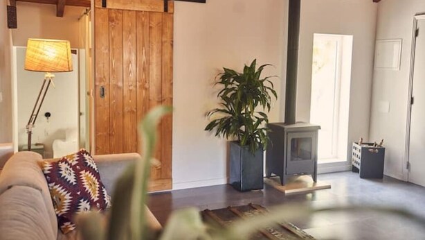Ein gemütliches Wohnzimmer mit Holztür, Kamin, Sofa und Lampe.