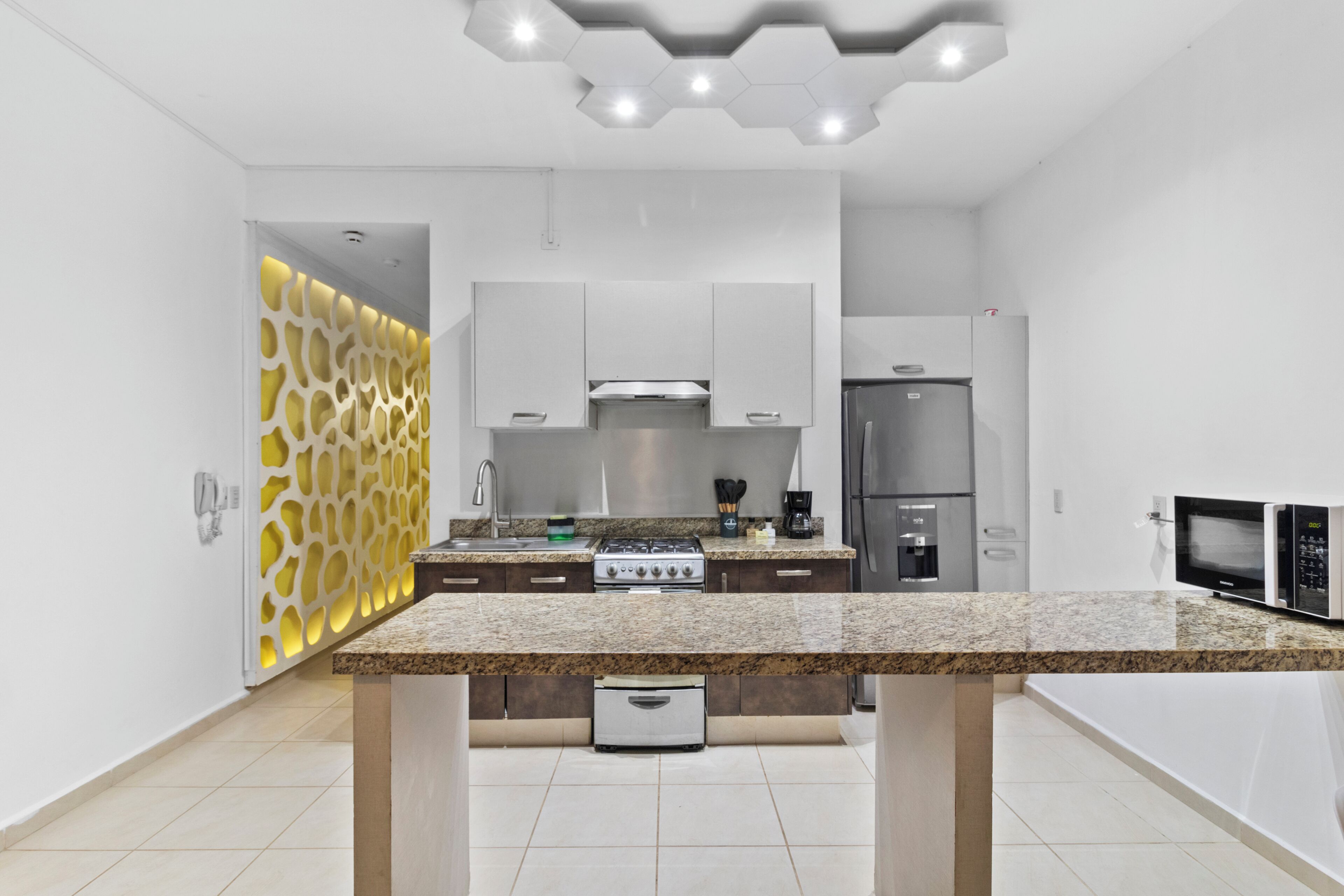 A modern kitchen with a granite countertop, stainless steel appliances, and a decorative wall panel.