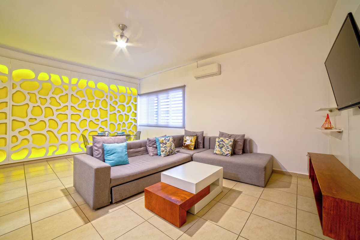A modern living room with a sectional sofa, a coffee table, and a decorative wall.