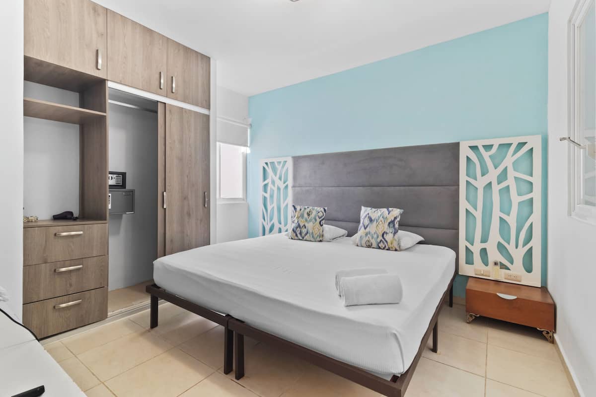 A bedroom with a bed, a wardrobe, a bedside table, and a decorative wall panel.
