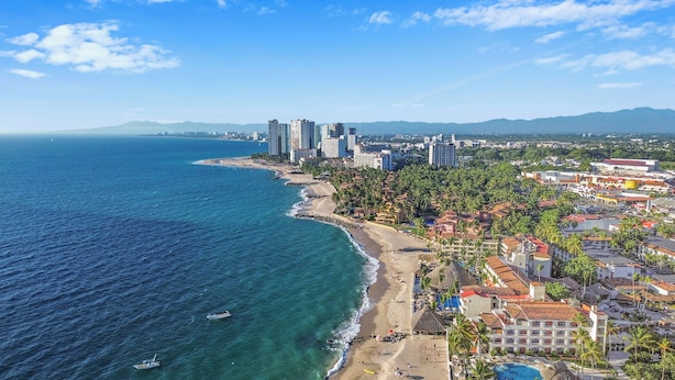 Un paisaje urbano costero con playa, rascacielos y cielo despejado.
