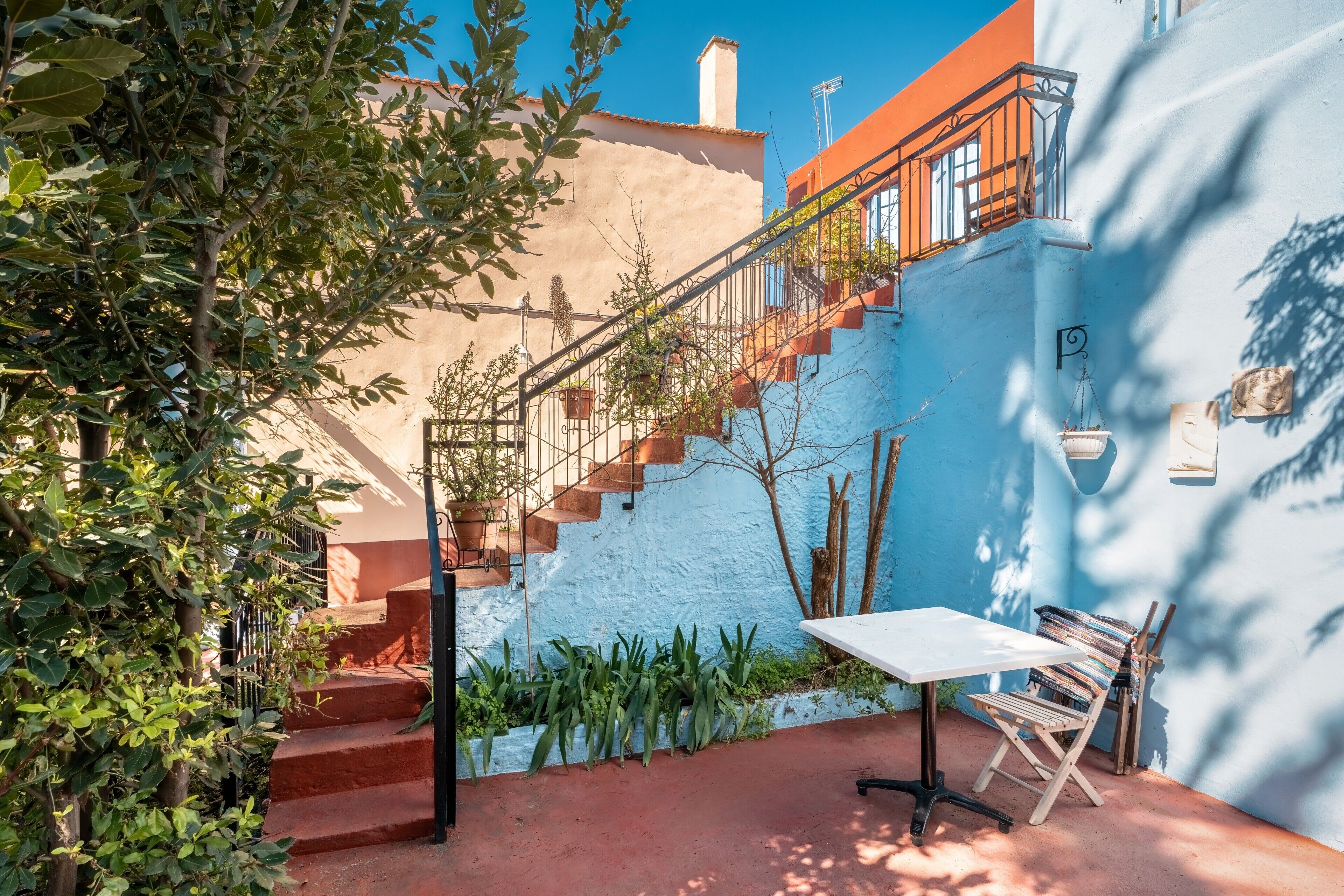A courtyard with a staircase, a table, and a bench.