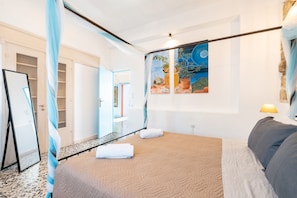 Una camera da letto con un letto, uno specchio, un quadro e una lampada.