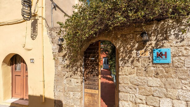 A stone building with a wooden door and an archway, a sign reading 'Katia's Home,' and a number '27' on the wall. - Holiday Home 'Katia's Home First Floor' with Shared Garden, Wi-Fi and Air Conditioning (Rhodes)