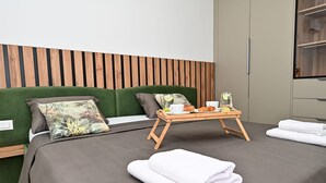 Una cama bien hecha con una bandeja de desayuno, un cabecero tapizado en verde y un panel de pared de madera.