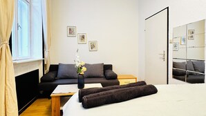 Ein modernes Hotelzimmer mit einem großen Bett, einer Couch, einem kleinen Tisch und einem Spiegel.