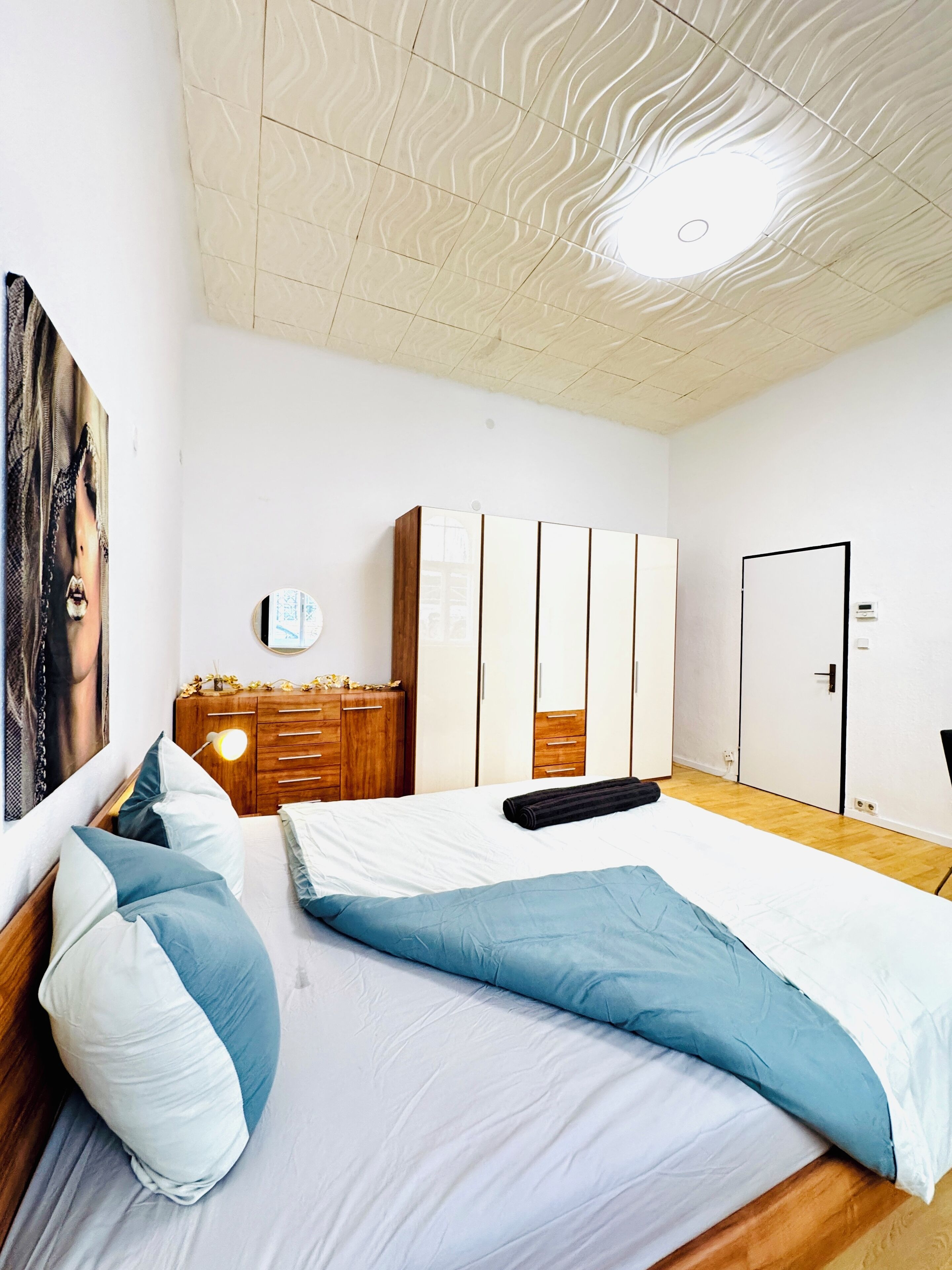 Une chambre à coucher avec un lit, une armoire en bois et une porte.