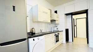Eine moderne Küche mit einem Edelstahl-Kühlschrank, einer eingebauten Waschmaschine und weißen Schränken.