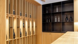 Una bodega con estantes de madera y estantes negros que contienen botellas de vino y cristalería.