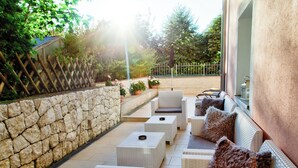 Un patio con mobiliario de mimbre, paredes de piedra y plantas en macetas.