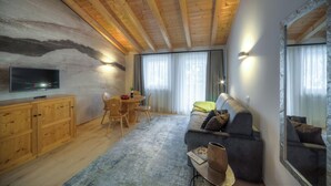 Una sala de estar acogedora con techo de madera, un sofá, un televisor y un comedor con mesa y sillas.