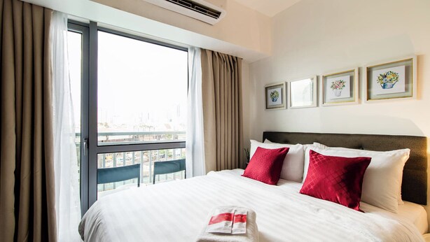 A hotel room with a large bed, a view of the city, and three framed pictures on the wall. - Cozy condo with AC in soothing near Rockwell (Mandaluyong City)