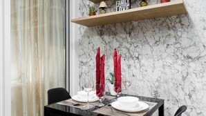 A dining table set with red napkins, white plates, and wine glasses against a marble wall. - Cozy condo with AC in soothing near Rockwell (Mandaluyong City)