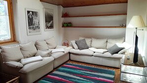 Un accogliente soggiorno con un divano componibile, un tappeto colorato a righe e un soffitto in legno.