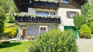 Un chalet a due piani con facciata in pietra, balconi in legno e una porta verde.