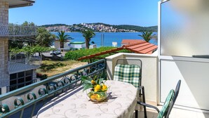 A balcony with a table, chairs, and a view of a coastal town. - Beachfront apartment fully equipped with terrace and seaview, parking included. (Okrug Gornji)