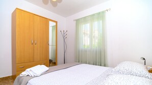 A bedroom with a bed, a wardrobe, a mirror, and a window with curtains. - Beachfront apartment fully equipped with terrace and seaview, parking included. (Okrug Gornji)