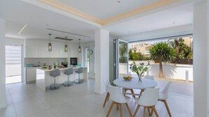 Une cuisine moderne avec des meubles blancs et un coin repas comprenant une table ronde et des chaises blanches.