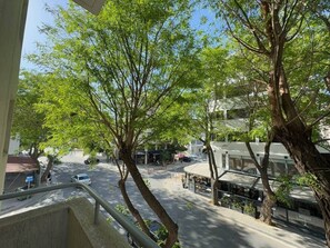 Une vue de rue avec des arbres, un café et un bâtiment doté d’un toit en pente.