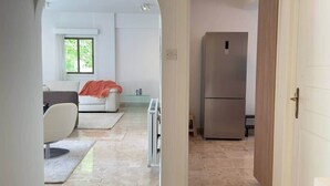 Een moderne keuken met een inbouwkoelkast en een eethoek met een witte tafel en stoelen.