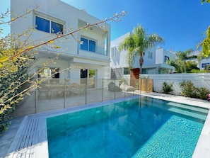 A modern two-story house with a swimming pool, a covered patio, and a view of neighboring houses. - Protaras Seaside Serenity - Konnos Beach (Paralimni)