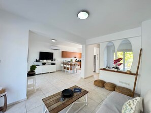 A modern living space with a kitchen, dining area, and a seating area with a sofa and coffee table. - Protaras Seaside Serenity - Konnos Beach (Paralimni)