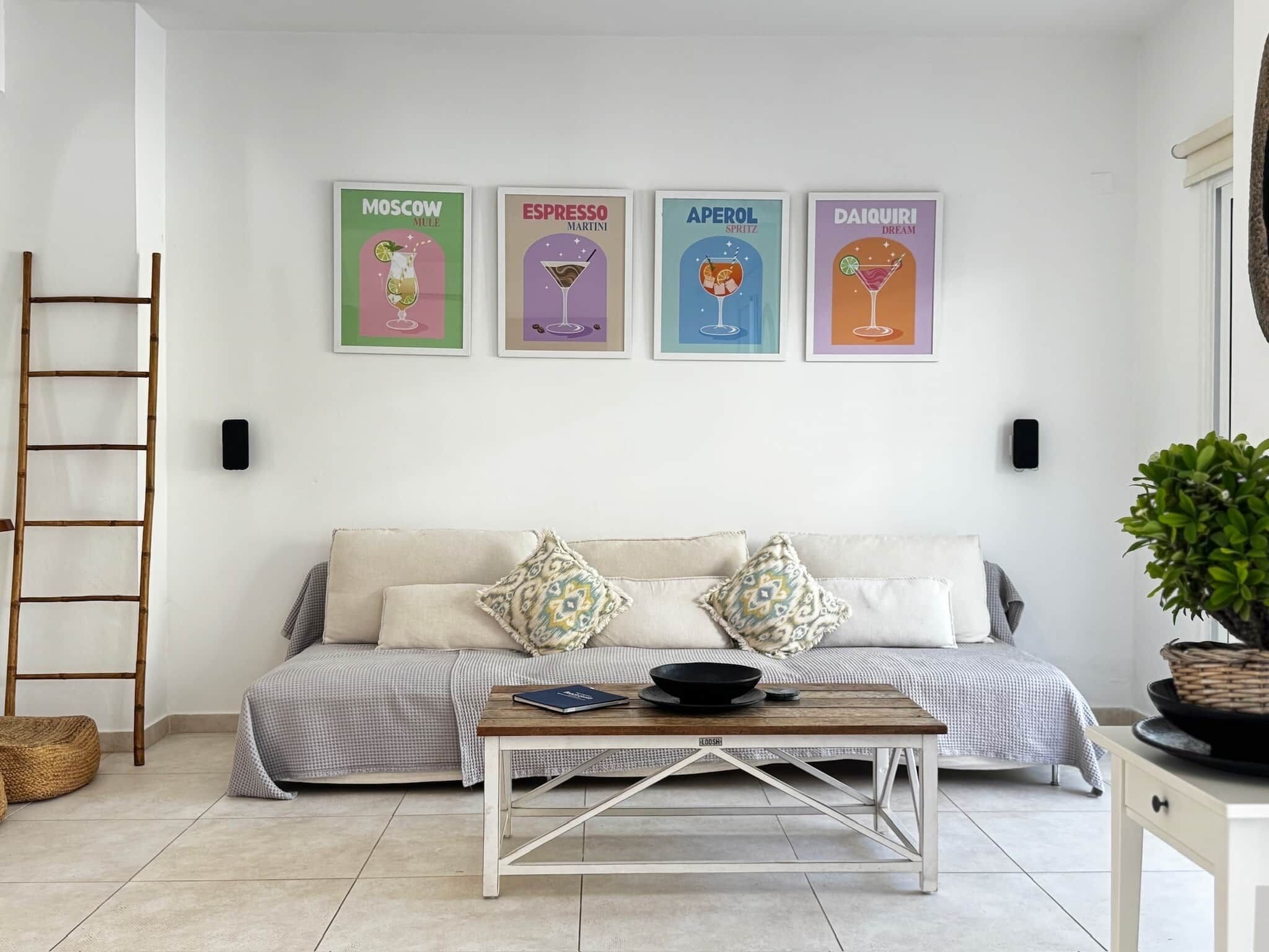 Ein Wohnzimmer mit einer Couch, einem Couchtisch und vier gerahmten Bildern an der Wand.
