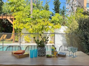 A poolside table with a book, salt and pepper shakers, a bottle, and glasses. - Protaras Seaside Serenity - Konnos Beach (Paralimni)