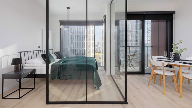 Ein modernes Schlafzimmer mit Bett, Nachttisch und Blick auf die Stadt durch große Fenster.