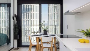 Eine moderne Küche mit Essbereich, großen Fenstern und Blick auf hohe Gebäude.