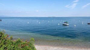 A calm lake with boats, clear water, and distant land. - Holiday Home 'Casa Liner - Steps From The Lake' with Lake View, Private Terrace and Wi-Fi (Moniga del Garda)