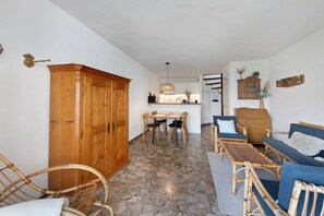 A room with a stone floor, wooden furniture, a dining area with chairs and a table, and a kitchen in the background. - Holiday Home 'Casa Liner - Steps From The Lake' with Lake View, Private Terrace and Wi-Fi (Moniga del Garda)