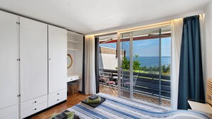 A bedroom with a bed, a wardrobe, a balcony with a view of the sea, and a table with chairs. - Holiday Home 'Casa Liner - Steps From The Lake' with Lake View, Private Terrace and Wi-Fi (Moniga del Garda)