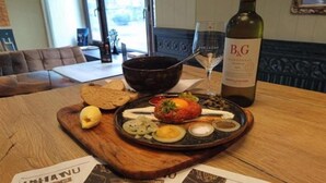Une table à manger avec une assiette de nourriture, une bouteille de vin et un verre.